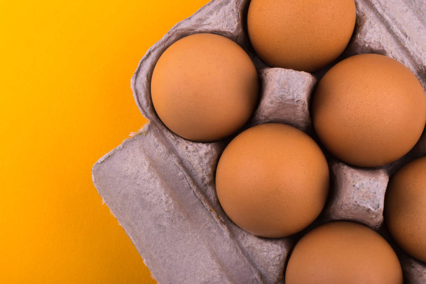 Brown chicken eggs in a tray lie on an orange background - 写真・画像