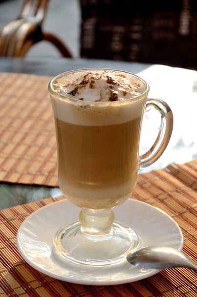 Cappuccino güneşli bir günde parkta, bir yaz kafede bir masada bir cam fincan. - Fotoğraf, Görsel