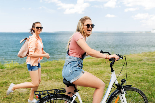 teenage girls or friends with bicycle in summer - Фото, зображення