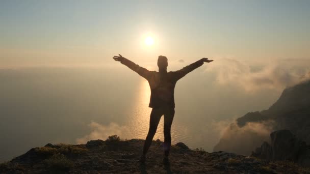Silueta de una mujer joven brazos extendidos observando una hermosa puesta de sol dramática sobre un mar desde una alta montaña en Crimea
. - Metraje, vídeo