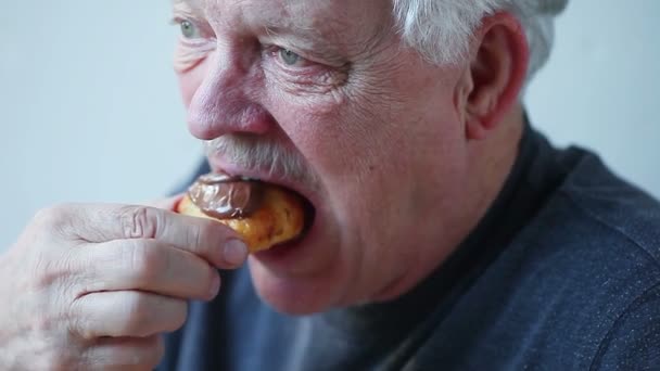 Older man enjoys a mini croissant covered with chocolate spread - Filmati, video