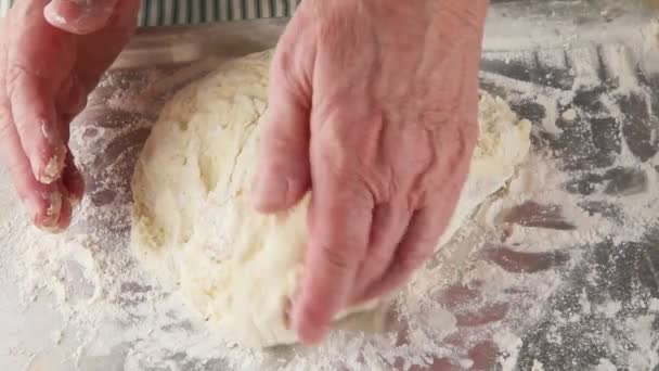 Um homem dobra e mistura uma massa pegajosa em uma superfície com farinhas
 - Filmagem, Vídeo