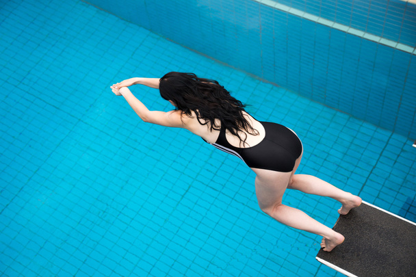 woman jumps from a spring board at swimming pool - Zdjęcie, obraz