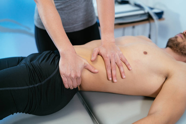 Photo detail of the hands of a physiotherapist massaging the belly and waist of a patient lying down. Concept of muscle health and relaxation.  - Foto, Imagem