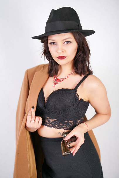 stijlvolle jonge vrouw in zwarte retro jurk en met Mans jas en hoed - Foto, afbeelding
