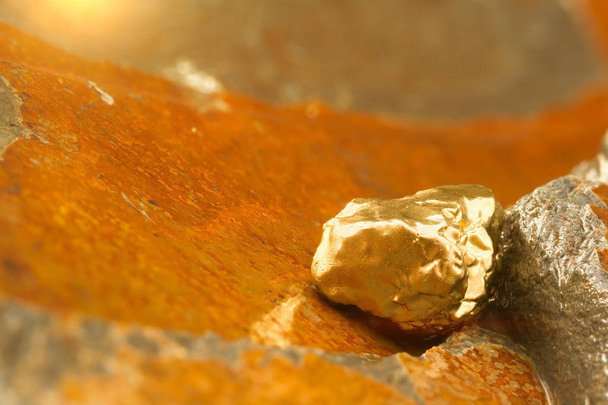Het zuivere gouderts gevonden in de mijn op een natte steen bij de rivier. Gouden bar in de natuur met glanzend zonlicht close-up. Succes en beleggen concept imago. - Foto, afbeelding
