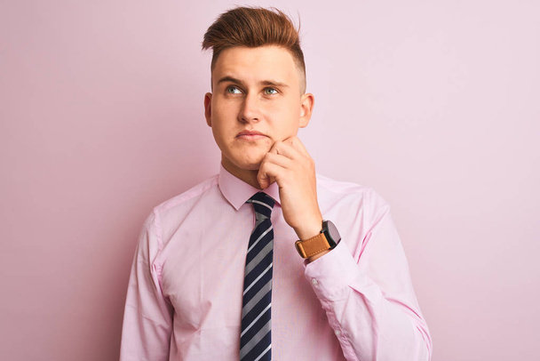 Young handsome businessman wearing shirt and tie standing over isolated pink background with hand on chin thinking about question, pensive expression. Smiling with thoughtful face. Doubt concept. - Photo, Image