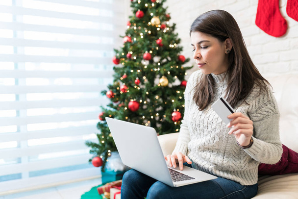 ミッド大人の女性のショッピングクリスマスプレゼントは、自宅でラップトップ上でオンライン - 写真・画像