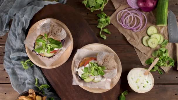 Hambúrguer vegan saudável com legumes frescos e molho de iogurte na bancada da cozinha rústica. - Filmagem, Vídeo