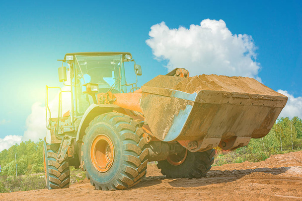 青空に対する建設現場の黄色い掘削機。土工作業中の砂場のホイールローダー - 写真・画像