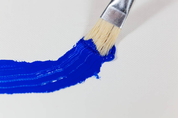 Paintbrush with blue color on a canvas background - Photo, Image