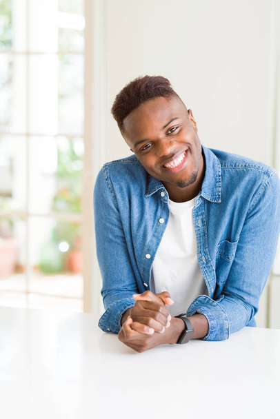 schöner afrikanischer junger Mann lächelt fröhlich mit einem breiten Lächeln auf  - Foto, Bild