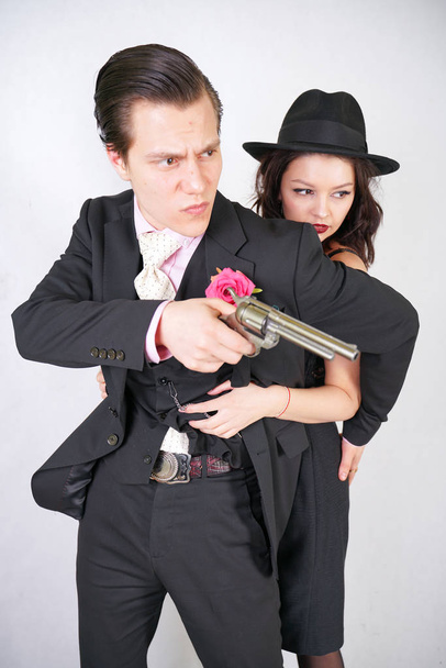 hombre en traje clásico con pistola proteger a su novia en fondo de estudio blanco
 - Foto, Imagen