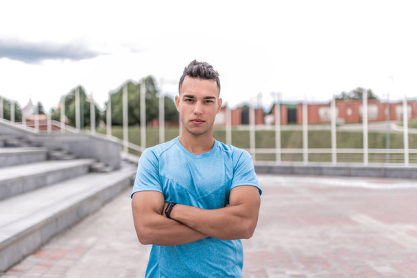 Athletic male athlete, standing in the summer in city, motivation for doing fitness sport workout, in the morning at a workout. Active lifestyle of young people, powerful and stylish man. - Valokuva, kuva