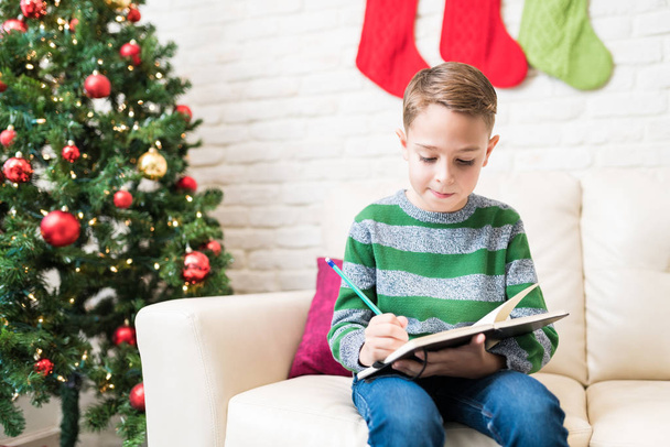 Kaukaski chłopiec piśmie Christmas list do Santa w domu  - Zdjęcie, obraz