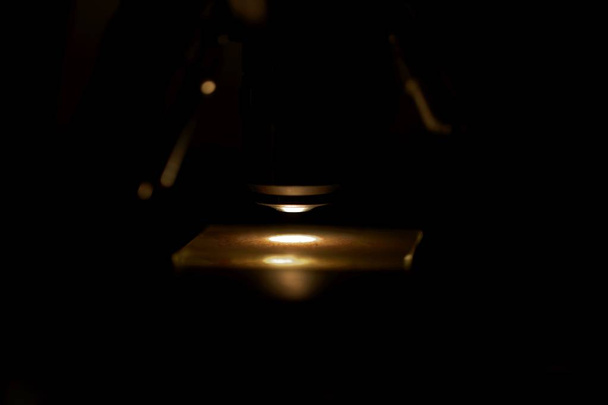 Objetivo del microscopio con una diapositiva y un fondo oscuro
 - Foto, imagen