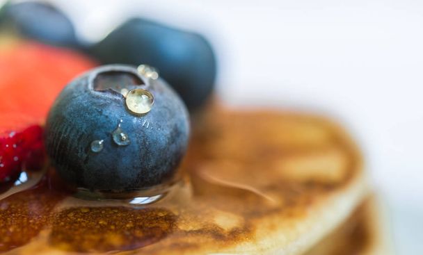 Close up of a blueberry with a drop of honey on the stack of pancakes. - Fotografie, Obrázek