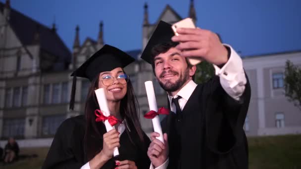 Garduate ζευγάρι κάνει μια selfie δείχνει διπλώματα στην κάμερα. - Πλάνα, βίντεο
