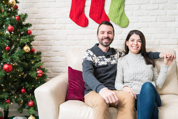 glückliches Paar sitzt auf dem Sofa und genießt den Weihnachtsurlaub zu Hause - Foto, Bild