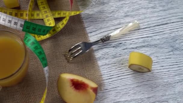 Peaches, juice and a fork on a sackcloth and a wooden table with a centimeter - Séquence, vidéo