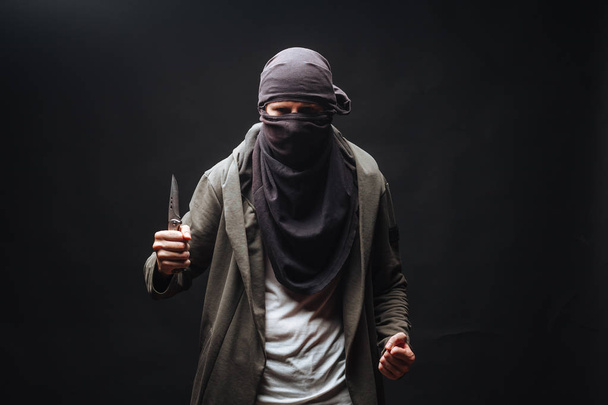 man met mes en masker op donkere achtergrond - Foto, afbeelding