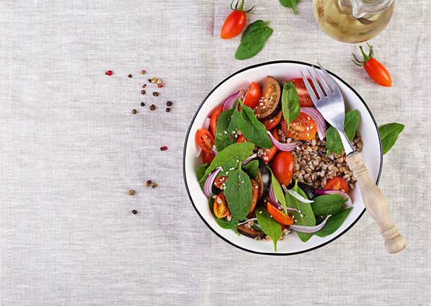 Buchweizensalat mit Kirschtomaten, roten Zwiebeln und frischem Spinat. Veganes Essen. Ernährungsmenü. Ansicht von oben. flache Lage - Foto, Bild