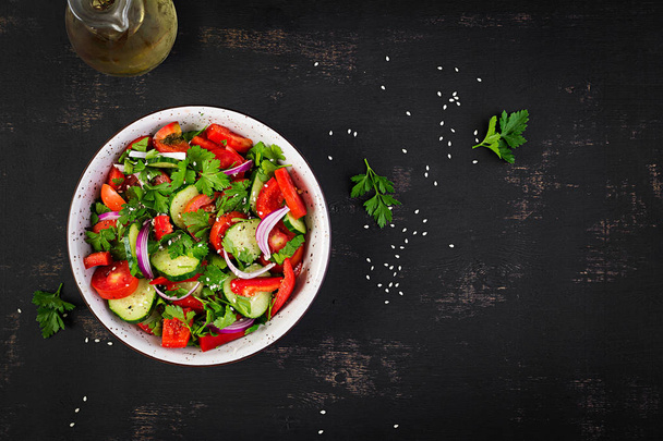 Tomaat en komkommer salade met rode ui, paprika, zwarte peper en peterselie. Veganistisch eten. Dieetmenu. Bovenaanzicht. Platte lay - Foto, afbeelding