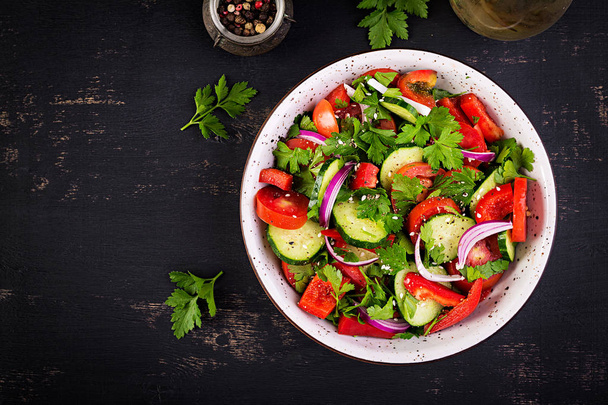 Tomato and cucumber salad with red onion, paprika, black pepper and parsley. Vegan food. Diet menu. Top view. Flat lay - Foto, Bild