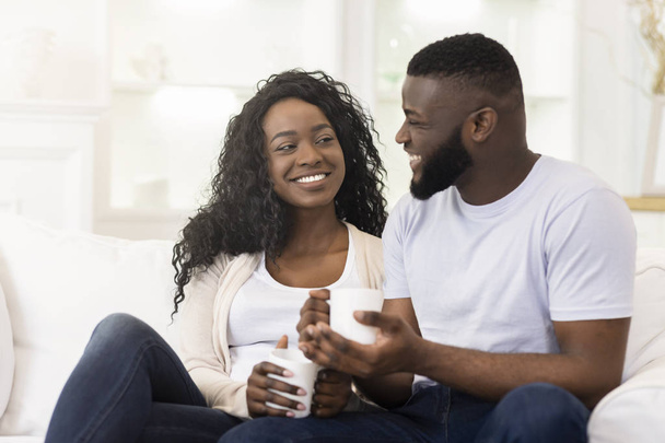 Loving millennial couple relaxing with cup of coffee at home - Photo, Image