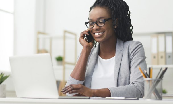 Szczęśliwy biznes dziewczyna mający rozmowa telefoniczna przy pomocy laptop w biuro - Zdjęcie, obraz