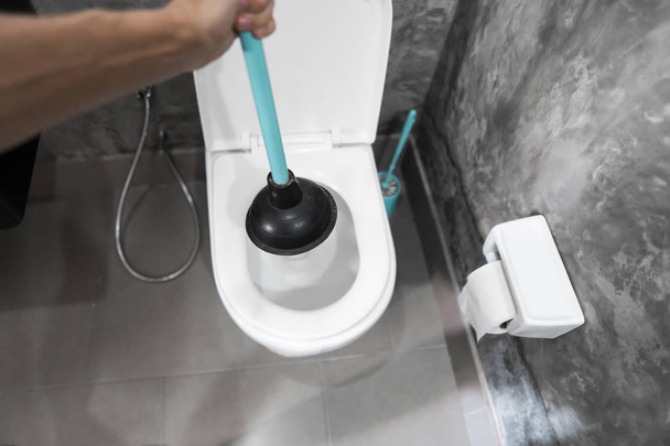 Toilet repair by hand with a Toilet Plunger. Plumbing. A plumber uses a plunger to unclog a toilet. Toilet Plunger. - Fotó, kép