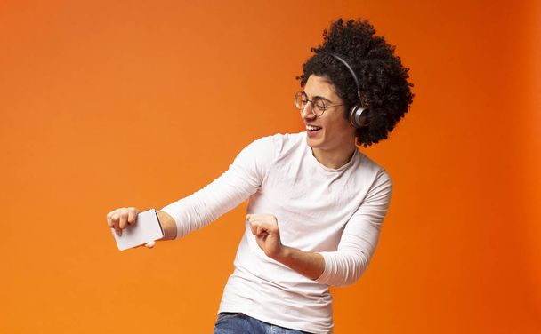 Aktywny beztroski czarny facet w bezprzewodowych słuchawkach korzystających z muzyki - Zdjęcie, obraz