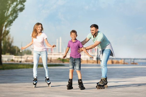 Happy family roller skating on city street - Foto, afbeelding