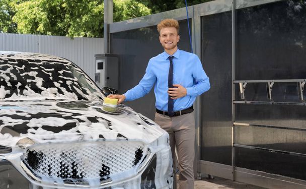 Businessman cleaning auto with sponge at self-service car wash - Zdjęcie, obraz