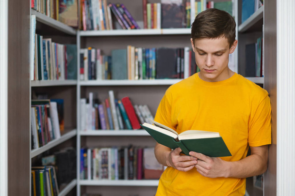 Розумний студент читає книгу між книжковими полицями
 - Фото, зображення