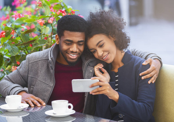 Молодая супружеская пара смотрит фотографии по мобильному телефону
 - Фото, изображение