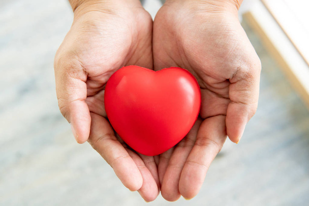 handen houden van rood rubber hart, liefde en zorgconcept - Foto, afbeelding