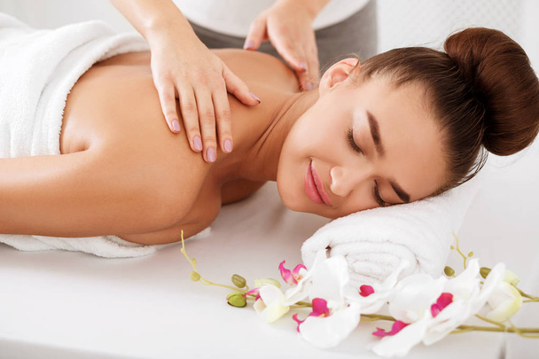 Жінка насолоджується масажем плечей, розслабляючись із закритими очима
 - Фото, зображення