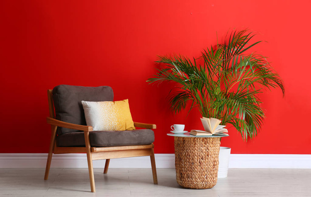 Stylish room interior with modern furniture and houseplant near red wall - Fotografie, Obrázek