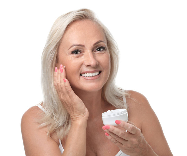 Portrait of beautiful mature woman with perfect skin holding jar of cream on white background - Fotó, kép