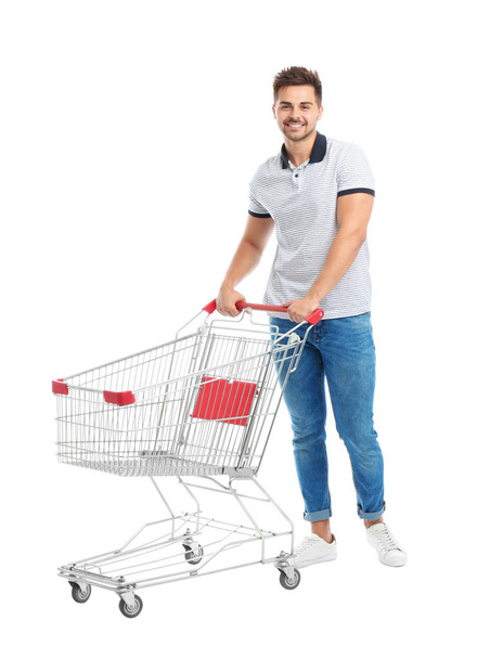 Young man with empty shopping cart on white background - Zdjęcie, obraz