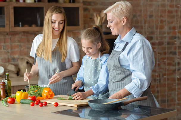 Gerijpte dames onderwijzen klein meisje hoe te koken - Foto, afbeelding