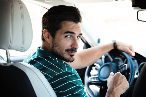 Ελκυστικός νέος άνθρωπος οδήγηση πολυτελές αυτοκίνητο, θέα από το πίσω κάθισμα - Φωτογραφία, εικόνα