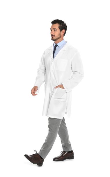 Young male doctor walking on white background. Medical service - Foto, afbeelding