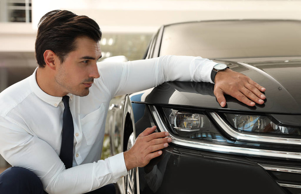 Young man checking new car in modern dealership - Фото, зображення
