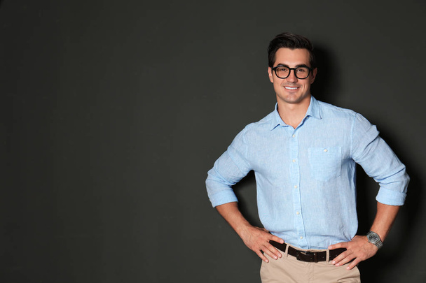 Handsome young man in stylish clothes with glasses on dark background. Space for text - Φωτογραφία, εικόνα