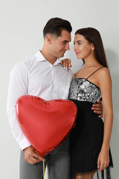 Beautiful couple with heart shaped balloon on light background - Фото, изображение