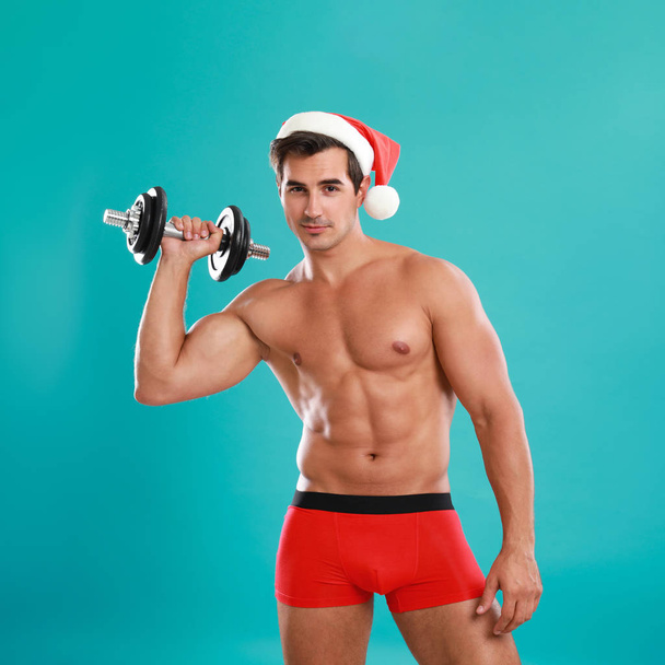 Sexy shirtless Santa Claus with dumbbell on blue background - Fotografie, Obrázek