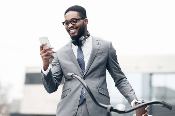 Hombre de negocios feliz usando el teléfono, de pie con la bicicleta
 - Foto, Imagen