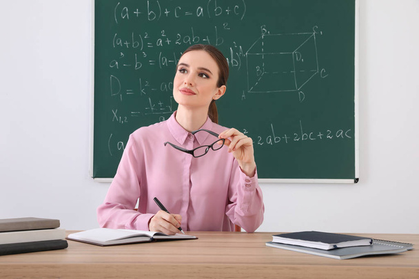 Portrait of young female teacher in classroom - Foto, imagen